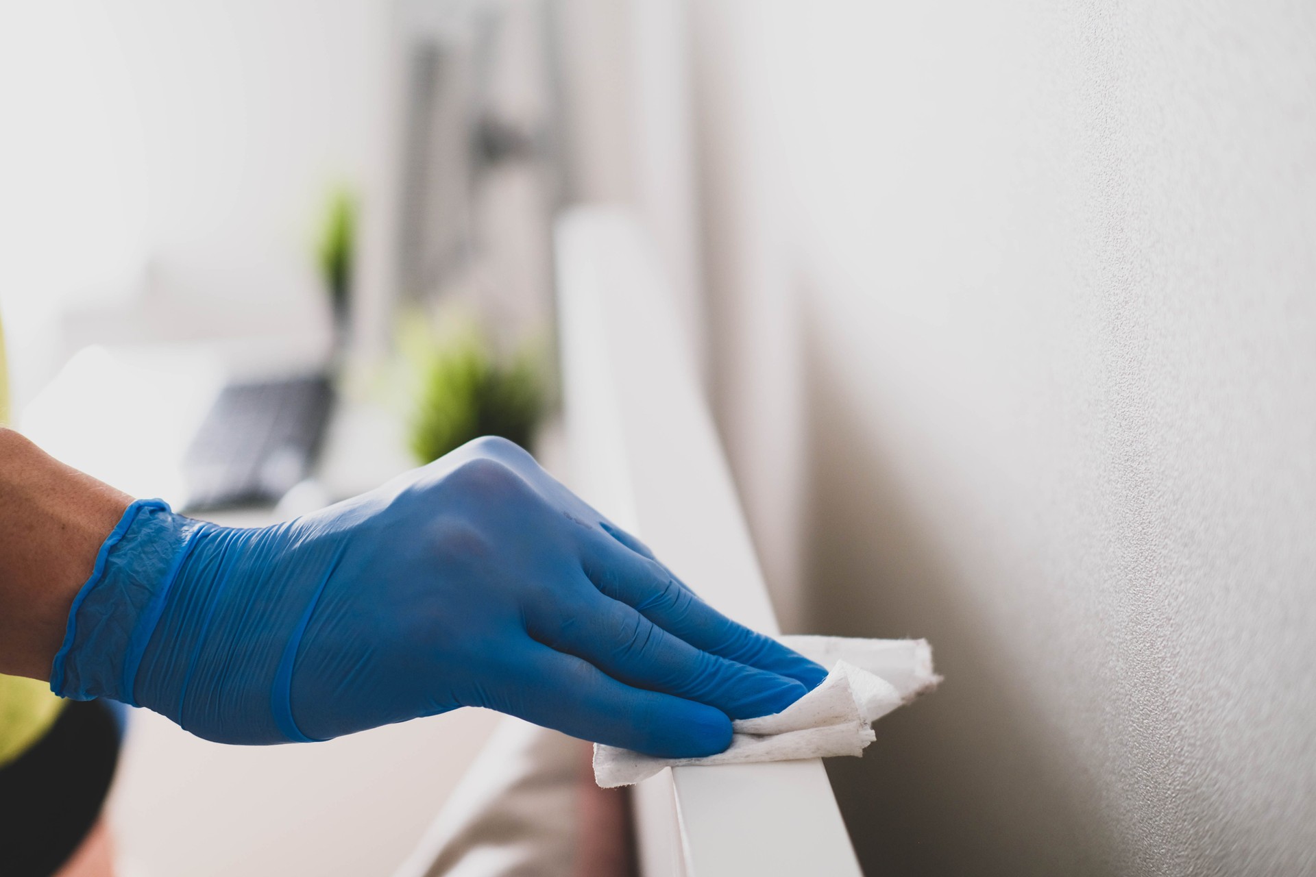 A man's hand in rubber gloves wipes the dust from the head of the bed with a napkin. Disinfection at home, cleaning in the context of the covid-19 pandemic.