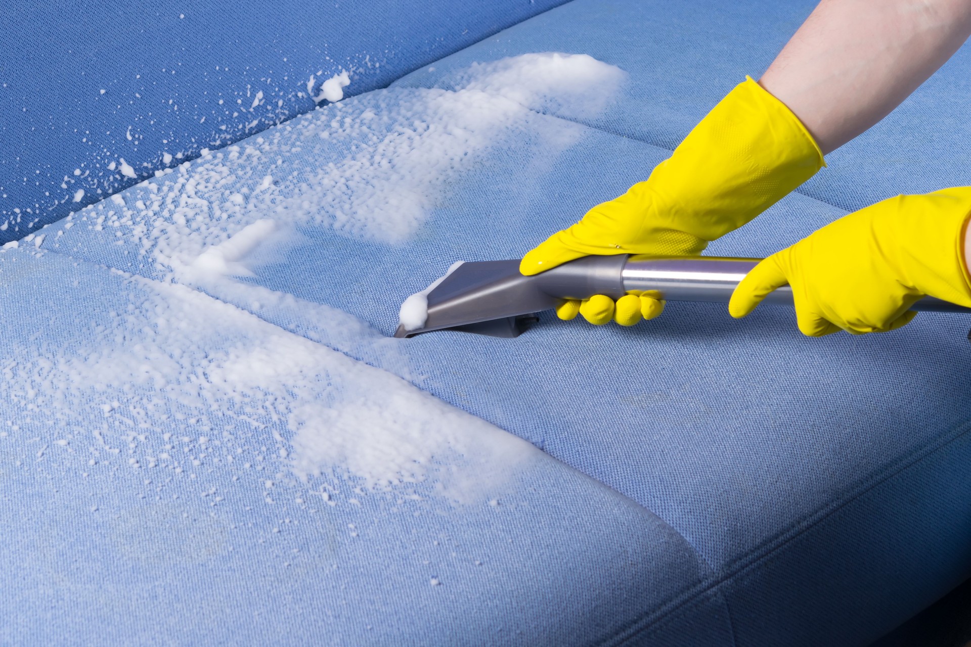 specialist in protective gloves, cleans the dirty sofa surface with a washing vacuum cleaner and foam, close-up yalova and izmit professional cleaning service